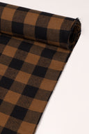 Gros plan sur le coin du tissu Le Carreau 009 caramel et noir à petits carreaux façon buffalo check, mettant en valeur le motif et la lisière effilochée.