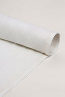 Tissu écru enroulé en rouleau, montrant le motif nuage tissé ton sur ton sur toute la longueur.