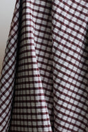 Close-up of the burgundy and ecru gingham check on the seersucker fabric, highlighting the irregular grain of the puckered texture.