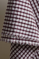 Close-up of the textured burgundy and ecru gingham seersucker cotton fabric, with the frayed selvedge visible.