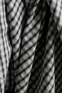Close-up of the textured black and white gingham seersucker cotton fabric, draped in tight folds.