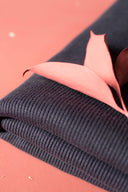 Piece of navy ribbing already cut into a ribbed cuff shape, placed on a white surface.