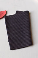 Folded navy ribbed ribbing, with a dried coral leaf placed on top, on a terracotta background.