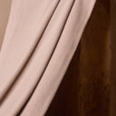 Close-up on the powder pink ribbed fabric, draped in diagonal folds against a wooden support.