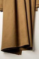 Gros plan sur les plis verticaux du tissu gabardine camel, mettant en valeur sa texture sergé mate.