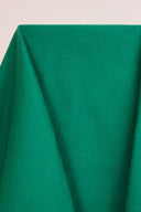 Gros plan sur les plis souples du tissu gabardine vert émeraude, mettant en valeur sa texture sergé mate.