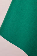 Tissu gabardine de coton vert émeraude, plié en pointe avec sa lisière visible.