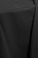 Tissu gabardine légère noir drapé en plis fluides sur l'angle d'un socle blanc.