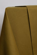 Gros plan sur les plis du tissu gabardine légère vert olive doré, laissant apparaître la texture sergé fine.