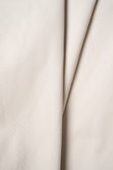 Tissu gabardine légère beige argile suspendu en plis fluides et asymétriques, drapé en pointe.