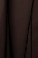 Close-up on the pointed fold of the chocolate brown light gabardine fabric, fine twill texture visible.