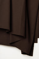 Close-up on the tight vertical folds of the chocolate brown light gabardine fabric.