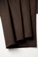 Gros plan très rapproché sur la texture sergée du tissu gabardine marron chocolat.