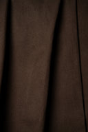 Tissu gabardine marron chocolat suspendu en plis verticaux fluides, lisière visible sur le côté.