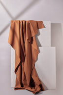 Gros plan sur les plis souples du tissu gabardine caramel, mettant en valeur sa texture sergé mate.