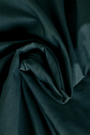 Close-up on the pine green cotton poplin fabric, forming a soft swirl.