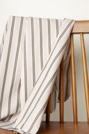 Weave Line fabric, off-white with vertical khaki and charcoal grey stripes, draped over the back of a wooden chair.